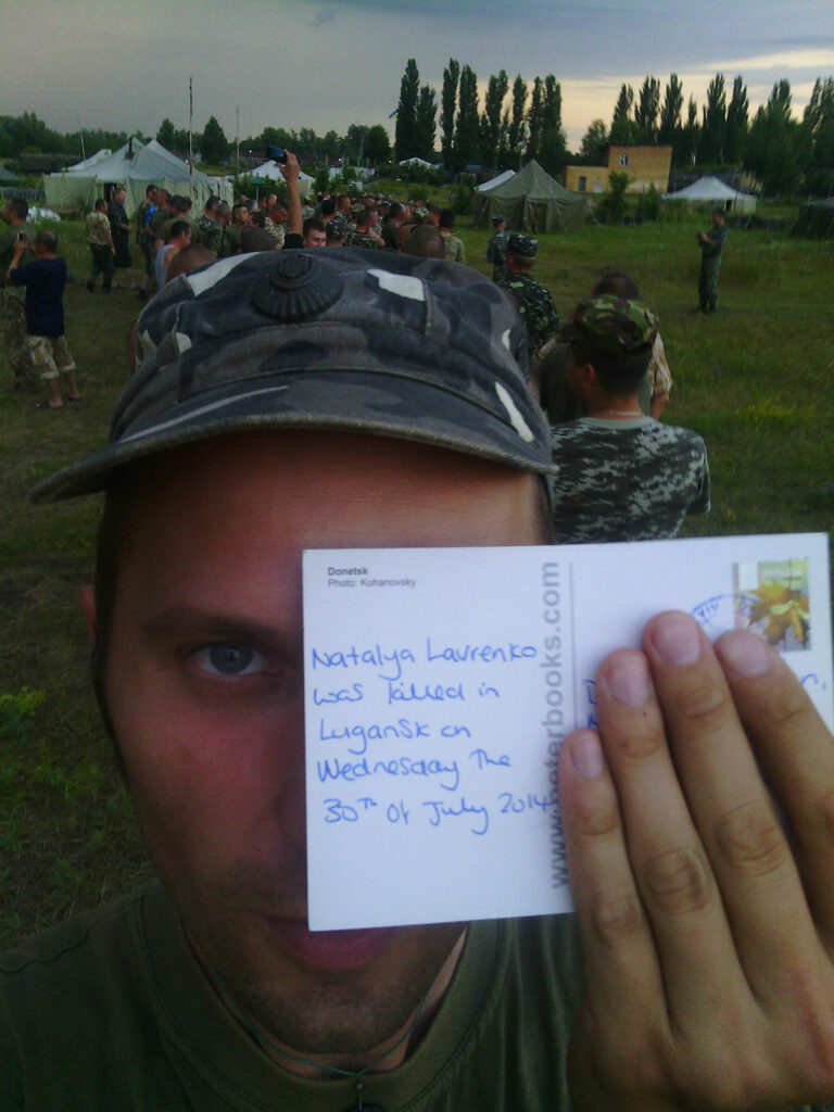 Dmitry, a serving officer in the Ukrainian Army, holds up the postcard he received.