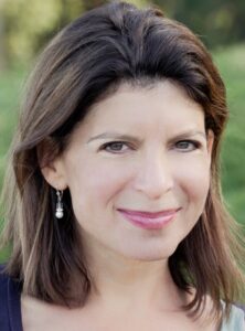 A Caucasian woman, brunette with brown eyes, smiles gently