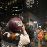 A building in Portland has a message projected onto it: "Fed goons out of PDX."