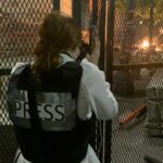 Eddy Binford-Ross shoots a photo from behind a fence