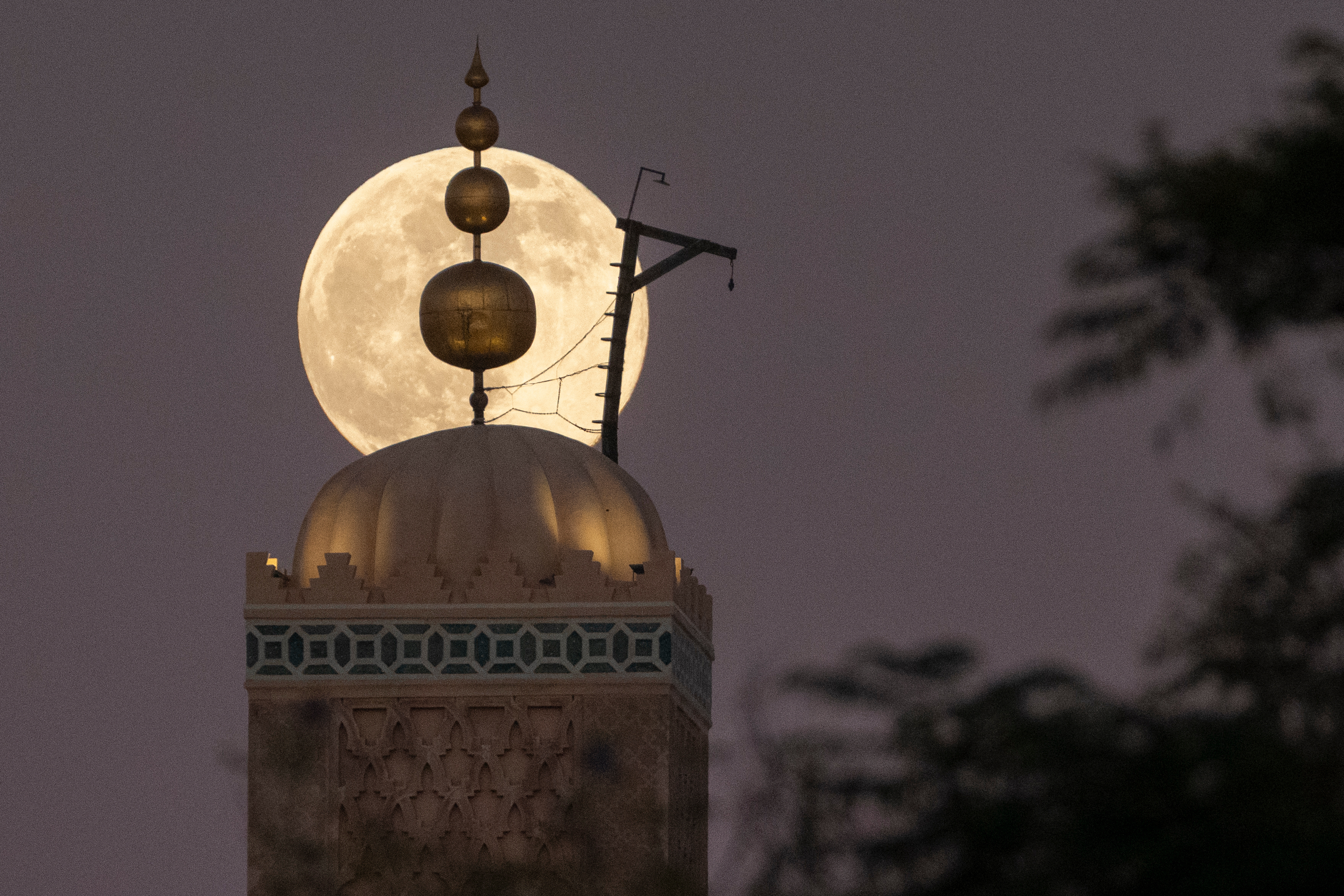 A supermoon, the last full moon of the year, rises up behind 12th century Koutoubia mosque in Marrakech, Morocco, Thursday, Dec. 4, 2025. (AP Photo/Mosa'ab Elshamy)
