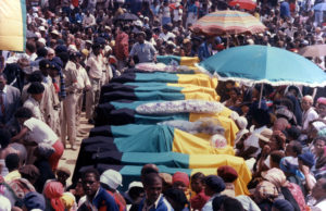 Mourners cluster around coffins draped in the flags of the then-banned ANC at the funeral of 17 blacks killed in Alexandra township in 1986.