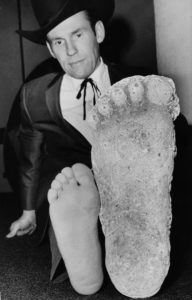 In this 1967 photo,  Roger Patterson compares his foot with a cast he says he made of Bigfoot in Northern California.