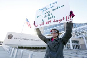 A woman holds a poster memorializing James Craig Anderson in front of the federal courthouse in Jackson, Miss.