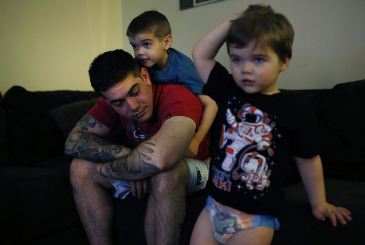 Jayson Morton plays with his sons, Eli, center, and Silas, at their home.