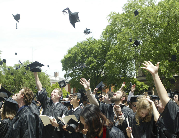 Brown University graduates throw their caps into the air. 