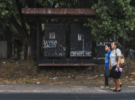 The bus stop in front of a Salvadoran battery factory with graffiti painted by community activists: “LIFE, HEALTH,” “RIGHTS.” 