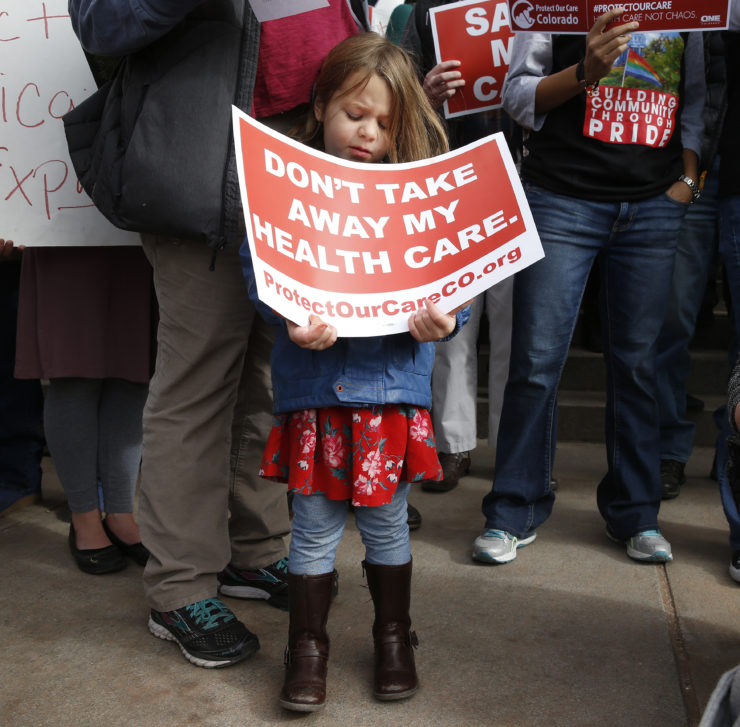 A girl stands holding a sign alongside supporters of the Affordable Care Act in Colorado. 