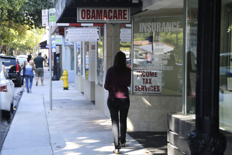 A woman walks past a sign advertising "Obamacare" in Miami. 