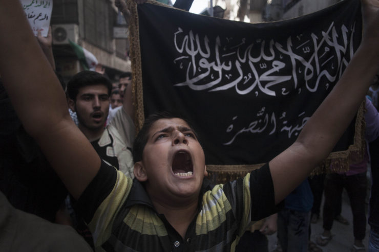 A Syrian boy shouts slogans against the Assad regime in front of a flag of the armed Islamic opposition group the Nusra Front during a demonstration in Aleppo in 2012. 
