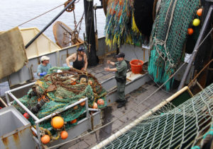 A Massachusetts Environmental Agency enforcement office talks to members of the crew on a fishing vessel before they offload their catch in New Bedford, Mass.