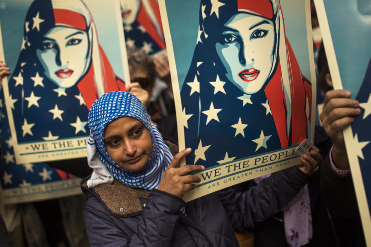People carry posters during a rally against President Trump's executive order banning travel from a list of Muslim-majority nations.