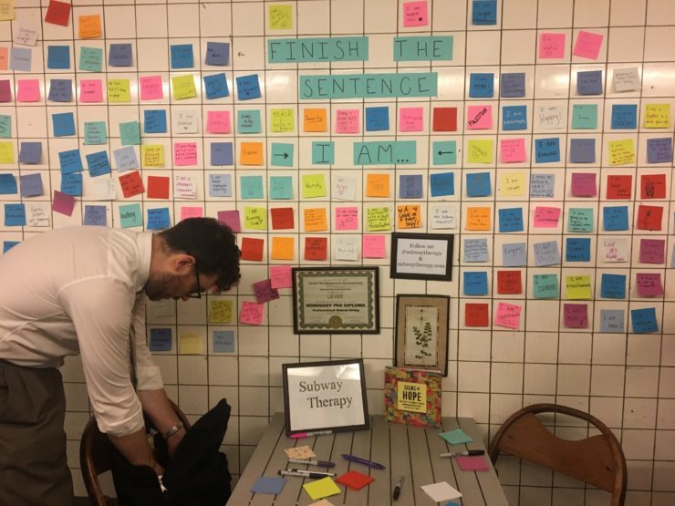 Subway Therapy's Levee in front of his sticky-note collage in the 14th Street station.