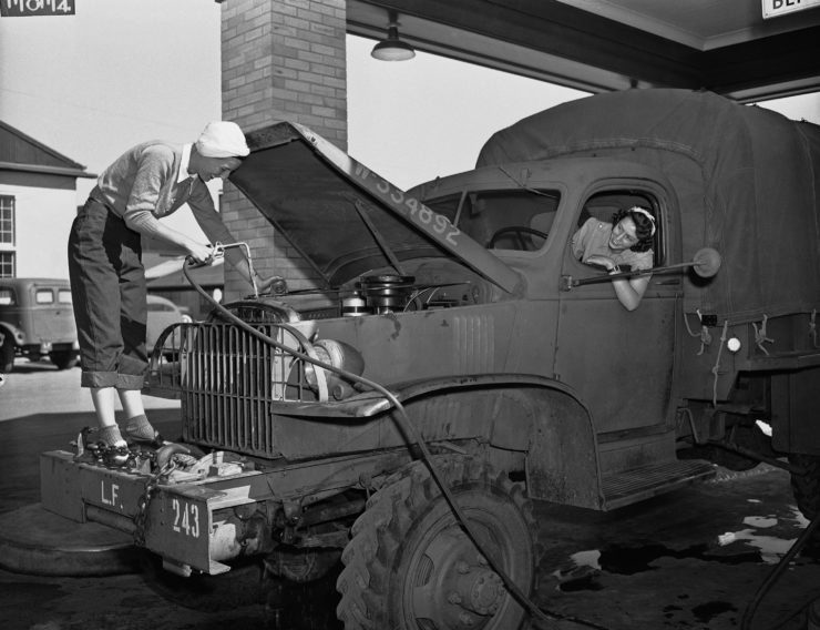 In this 1942 photo, a woman lifts up the hood of a truck. 