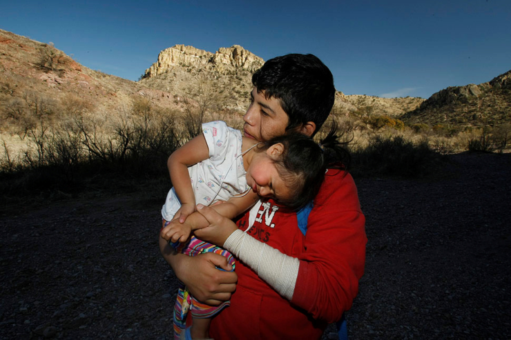 Luis Martinez holds his younger sister Amor during a visit to the river wash where they and their grandmother ended their nearly two-day walk with smugglers who guided them to Nogales, Ariz.