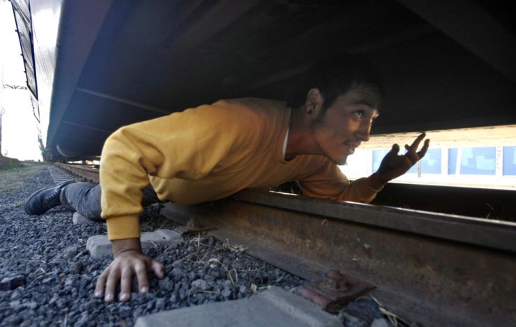 Lying on the rails, Luis Luna nervously tries to figure out how to crawl up into the undercarriage of the U.S.-bound freight car. 