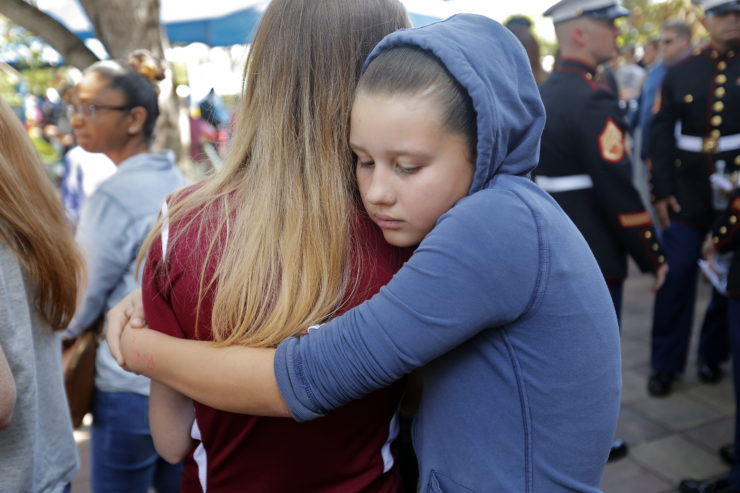 Kaitlynn Cooper, 12, right, hugs her friend Allison Shonk, 18, a student at Marjory Stoneman Douglas High School, during a vigil at after a mass shooting there. 