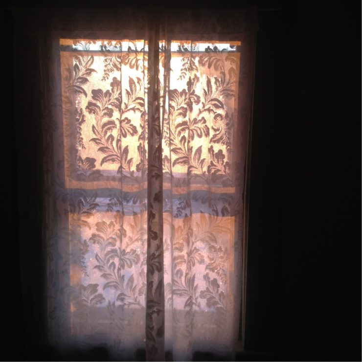 The sunrise of the winter solstice through a frost-covered window in the Maine countryside.