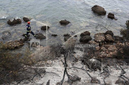 A member of a rescue team searches the area where burned trees hug the coastline in Mati, east of Athens.