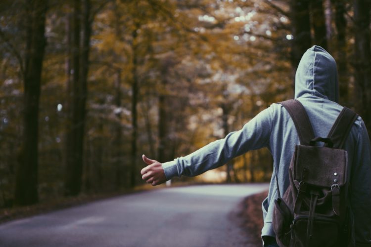 Man holds out arm with thumb pointed up to hitchhike