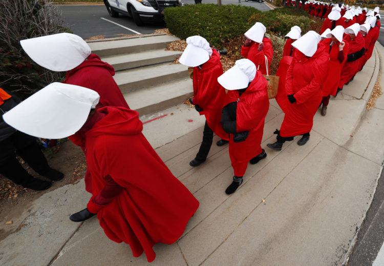 Women wearing "handmaids" costumes represented in the dystopian novels by Margaret Atwood protest an appearance by U.S. Vice President Michael Pence in Colorado in October, 2017. Pence is a staunch opponent of abortion rights.