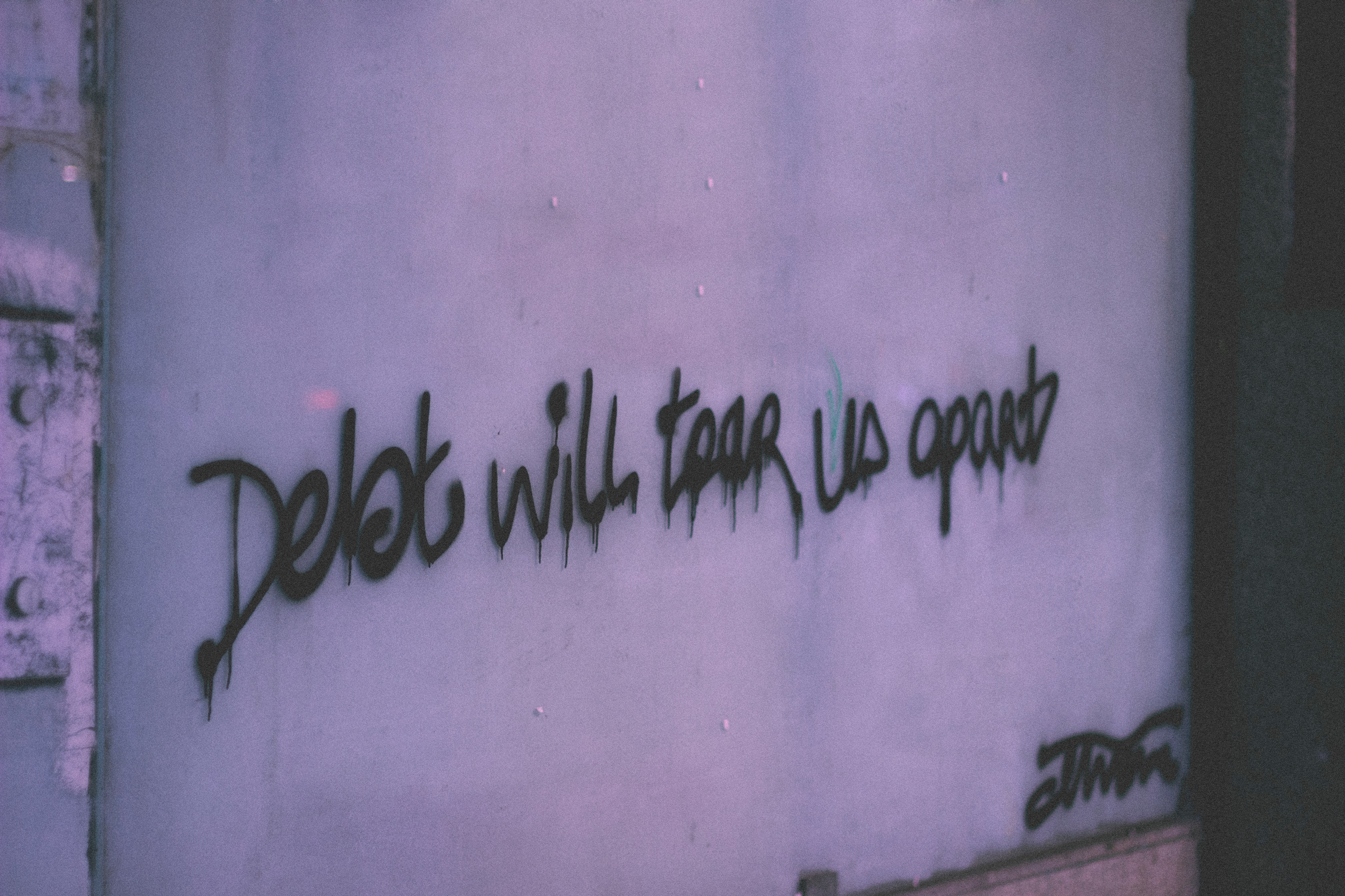 Stock photo of words on wall saying, "Debt will tear us apart."