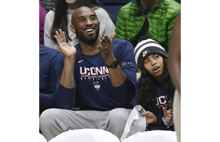 Kobe Bryant and his daughter Gianna watch the first half of an NCAA college basketball game in March 2019.