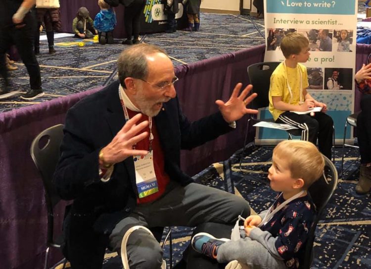 An evolutionary biologist talks to a child at the Science Storytellers booth.