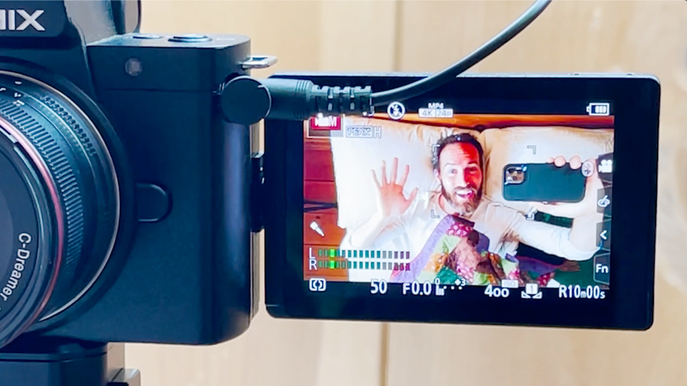 Alexander Trowbridge shoots a selfie video while waving to the camera with his free hand