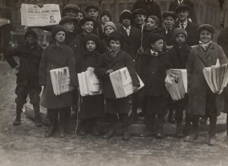 A historical picture of boys and young men holding newspapers