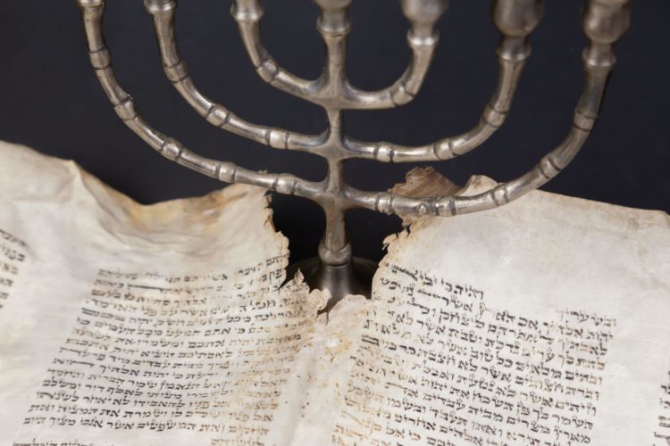 A menorah on a torn page of Hebrew
