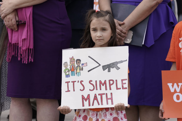 Child with sign at a gun violence protest in California in June 2022
