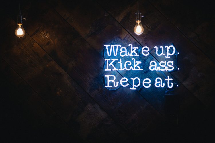 Neon sign that says WAKE UP KICK ASS REPEAT