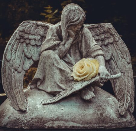 Sculpture of an angel holding a fresh rose.
