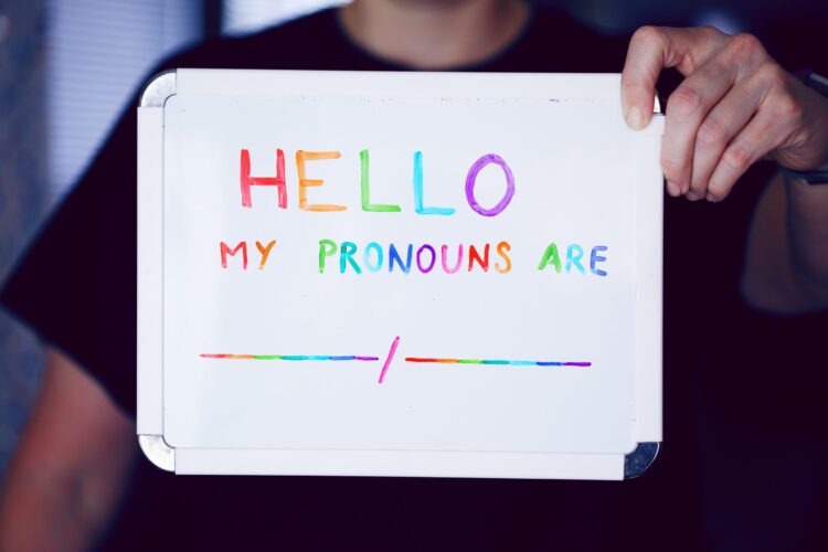 Photo of someone holding a sign saying "HELLO. My pronouns are _/_."