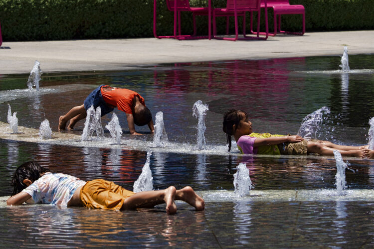 A photo of children cooling offin a fountain in downtown Los Angeles as record heat grips the south and west.