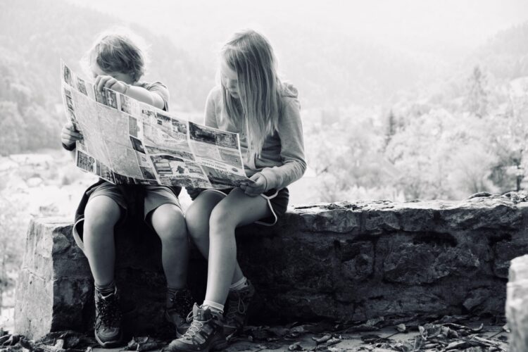 Two kids reading a newspaper
