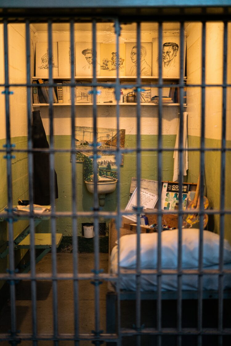 A photo of the interior of a prison cell decorated with hand-drawn portraits.