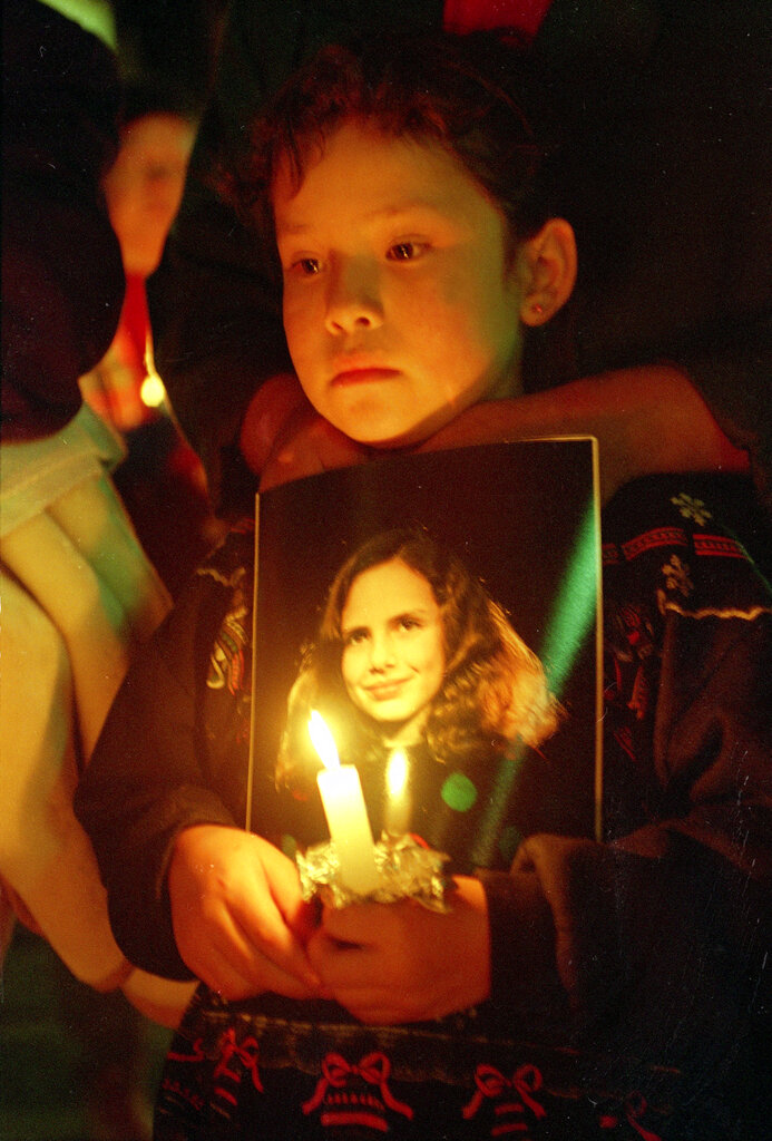 A child holds a photo of 12-year-old Polly Klaas at a memorial in Petaluma, California, a year after her kidnapping and murder.