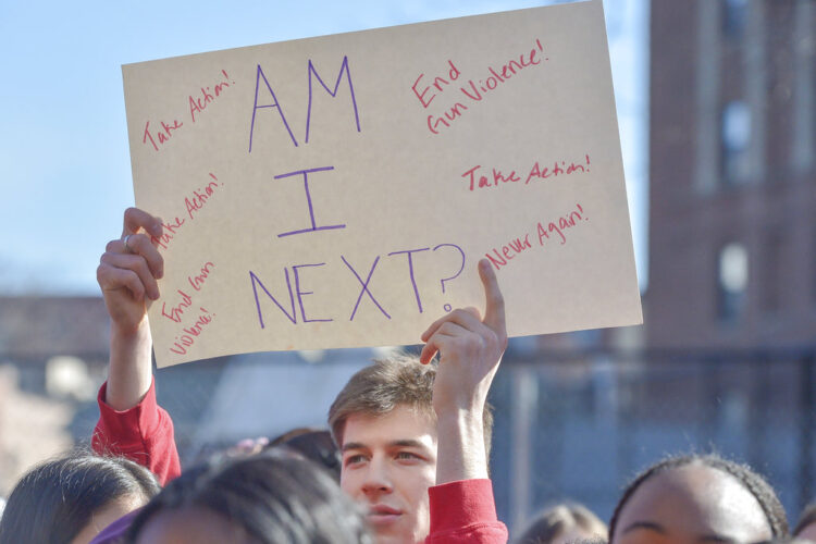 Photo of student at a rally for gun control, holding a sign that says AM I NEXT?