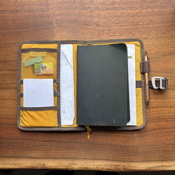 Inside pockets and notebooks of waxed field reporting journal.