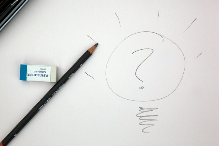 Photo of a pencil and eraser on a sheet of paper with a large question mark written on it