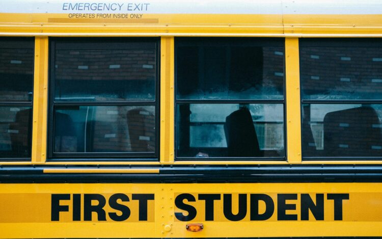 Close-up photo of the side of a school bus with the words FIRST STUDENT
